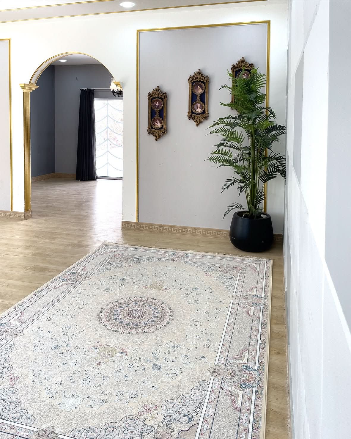 Alma Cream rug with a Persian-inspired central medallion in a room featuring gold-trim arches and a potted plant.