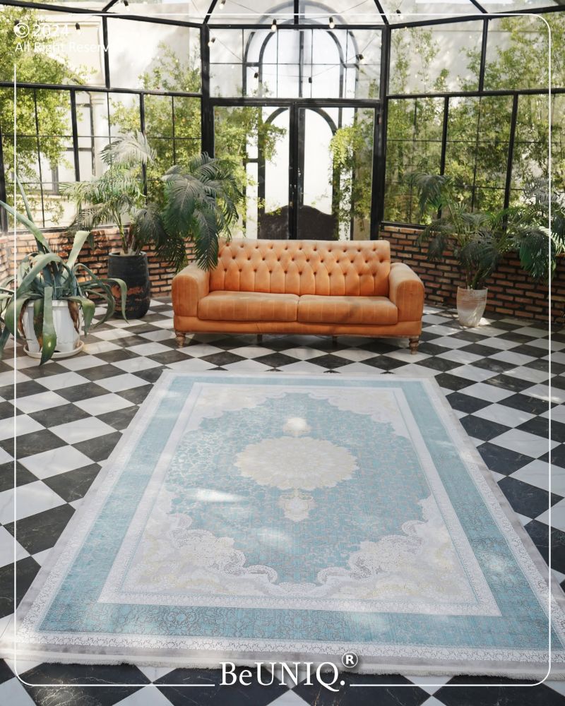 Orange sofa in a room with a decorative rug featuring clouds and the brand 'BeUNIQ'.